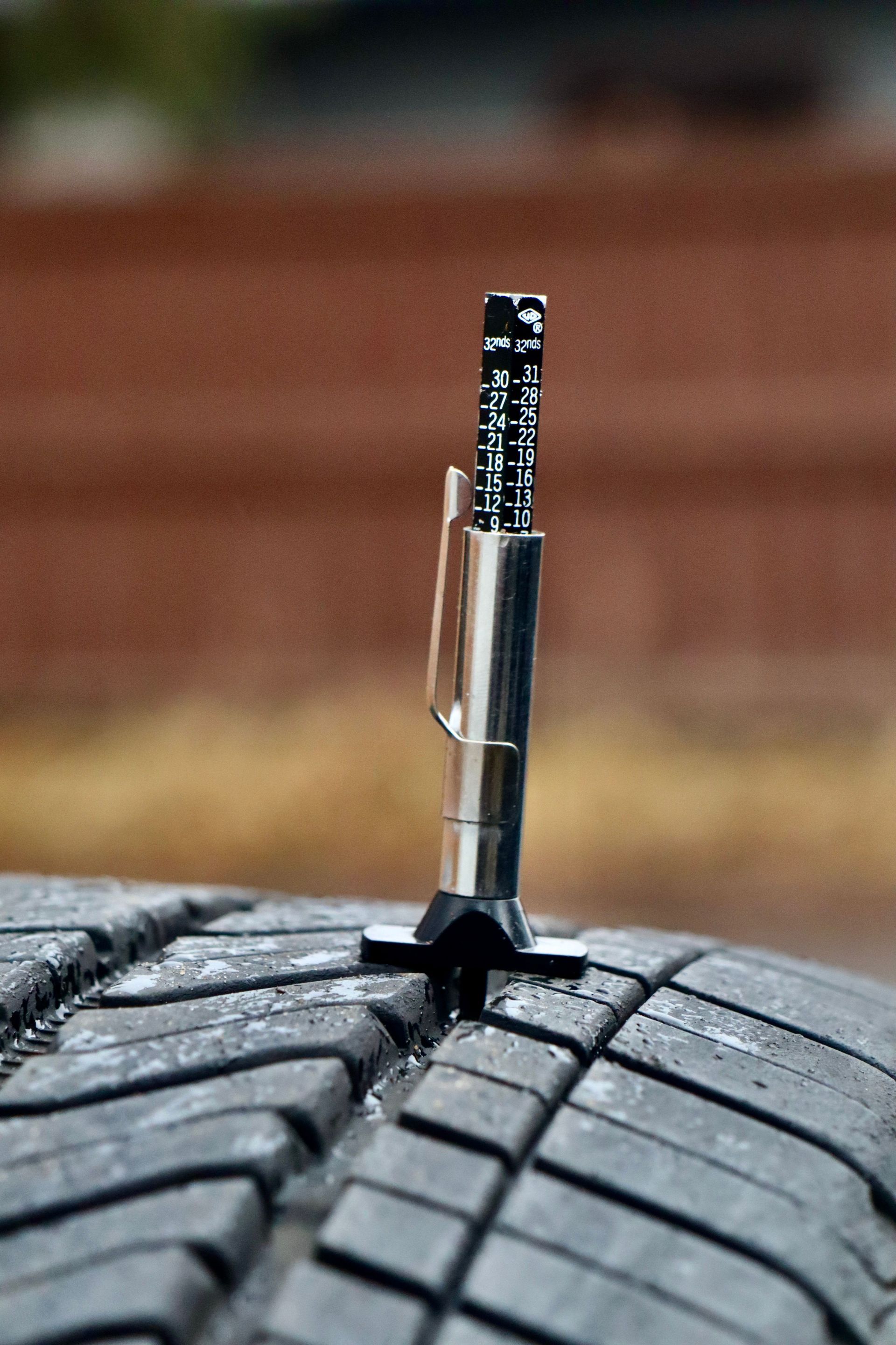 Close-up of a tire tread depth gauge in a tire illustrating measurement accuracy.