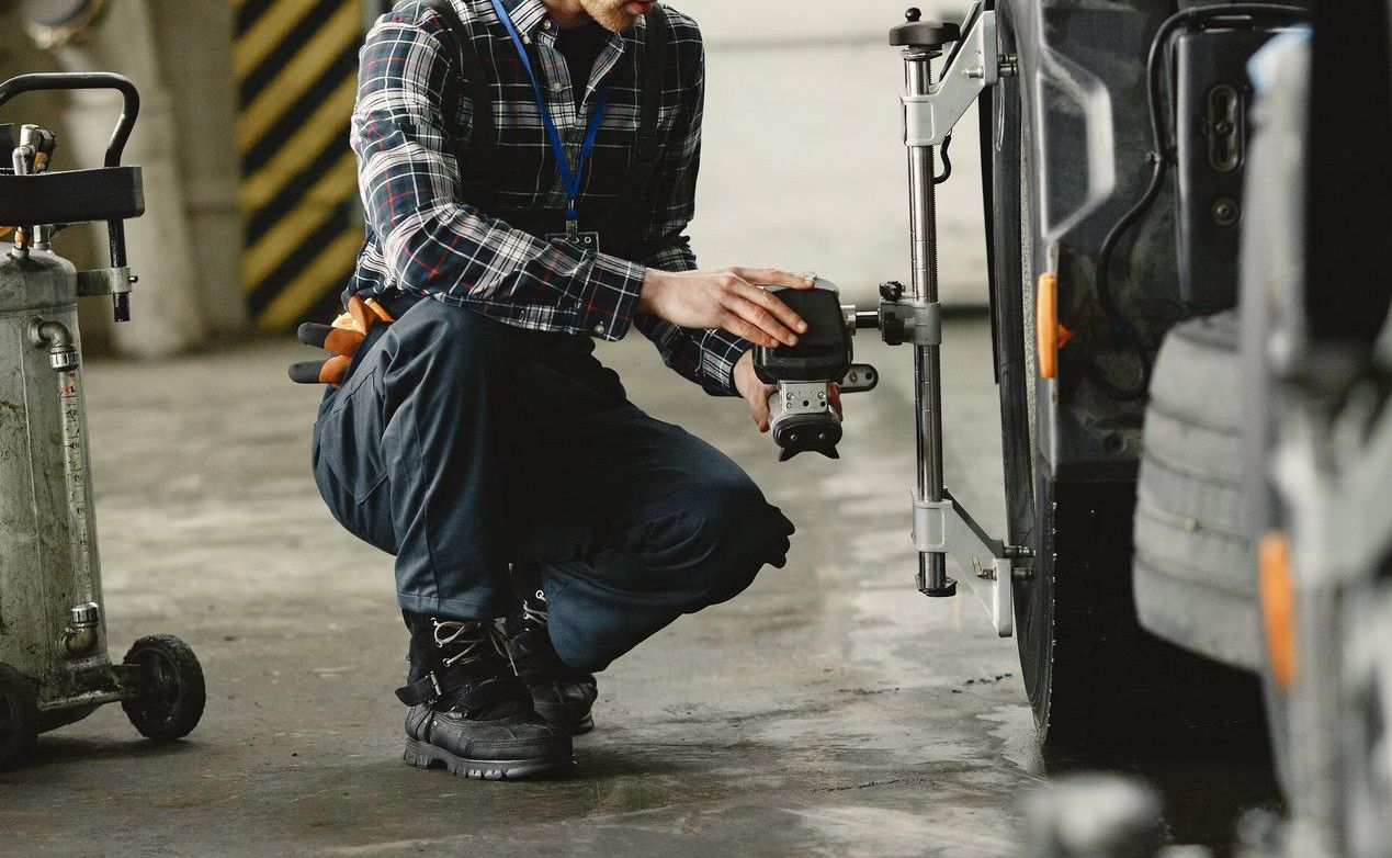 A mechanic in a workshop aligning truck wheels, focusing on precision and repair.